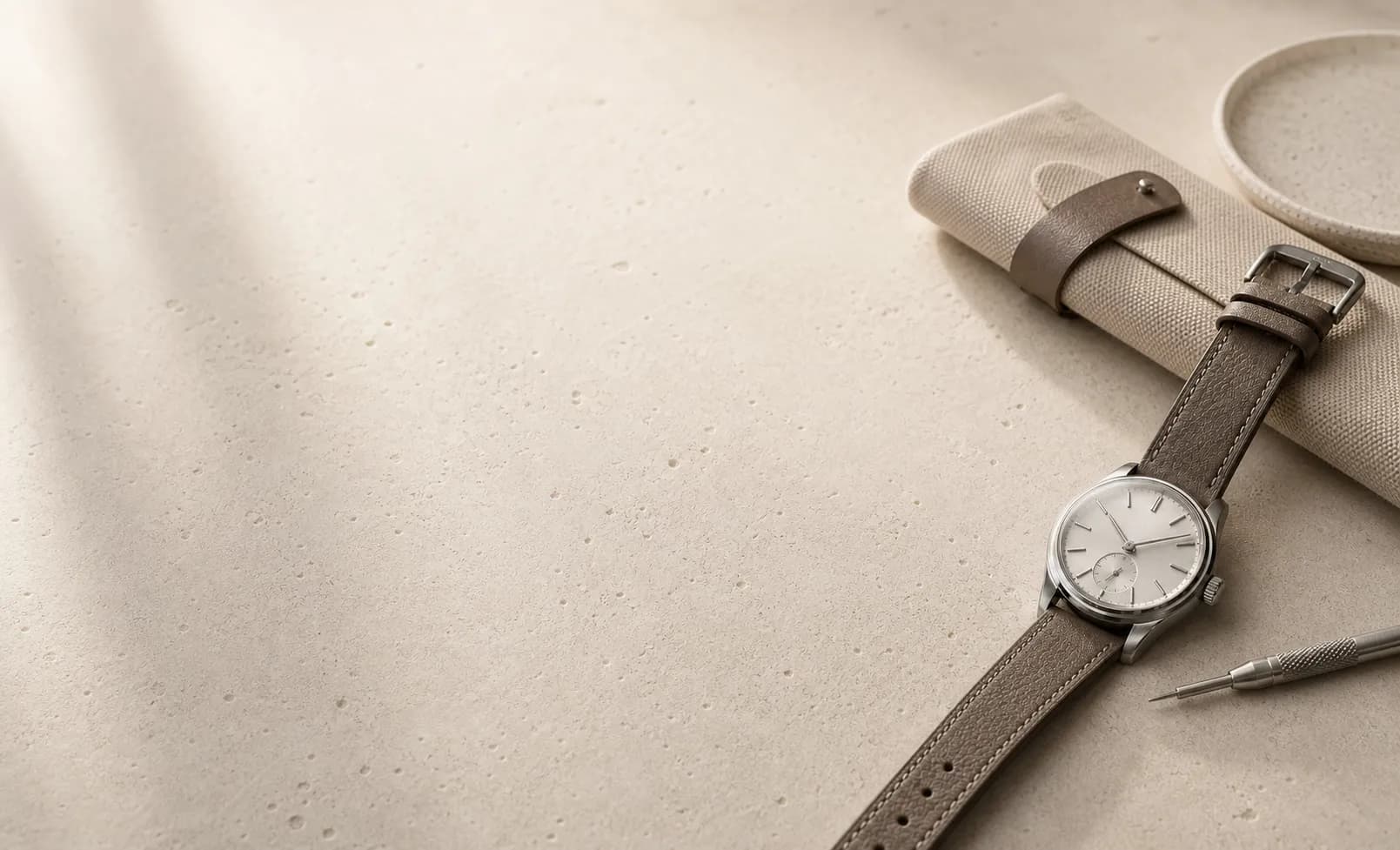 Traditional mechanical watch and understated strap on a quiet stone surface