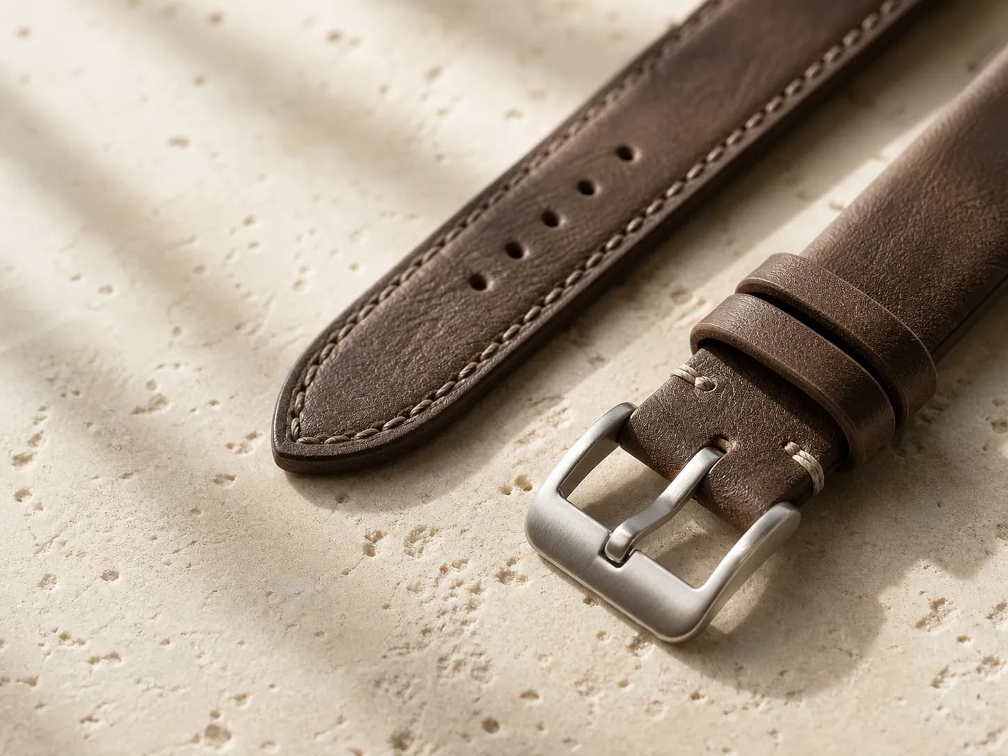 Restrained leather watch strap material detail on a warm light surface