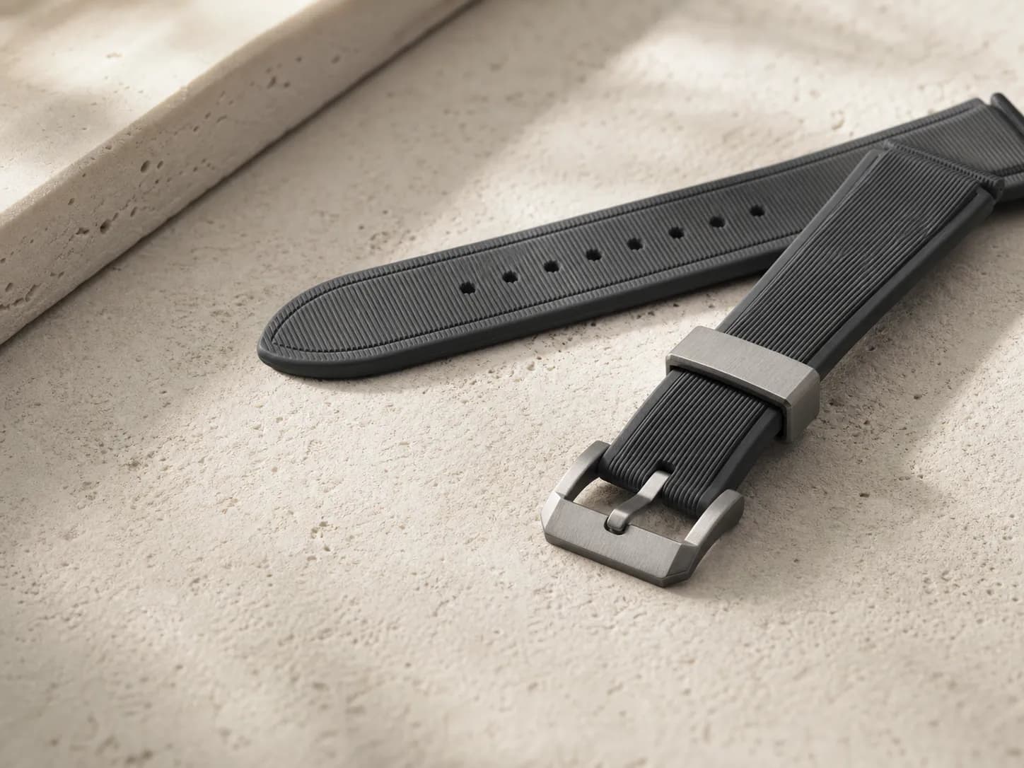 Matte rubber watch strap material detail on a warm light surface